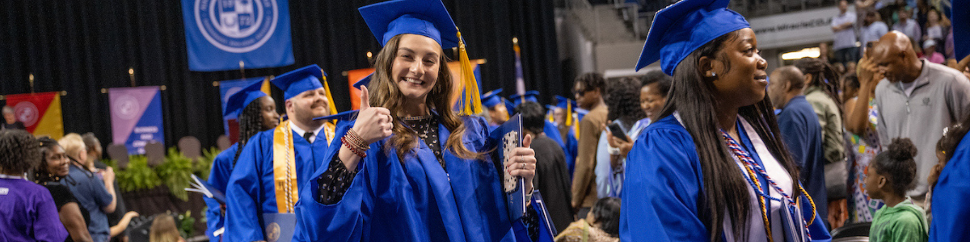 Photo of graduate giving thumbs up while in processional