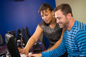 Female advisor assisting male student at computer station