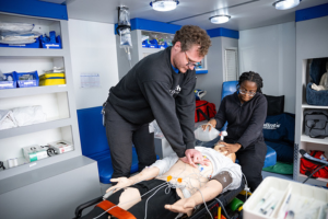 Two Aiken Technical College students practice emergency medical skills on a simulation mannequin during hands-on EMT training.
