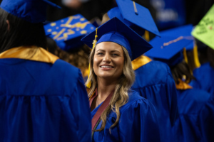Photo of student wearing royal blue regalia surrounded by fellow graduates