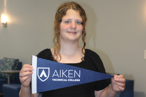 Student holding Aiken Technical College navy pennant